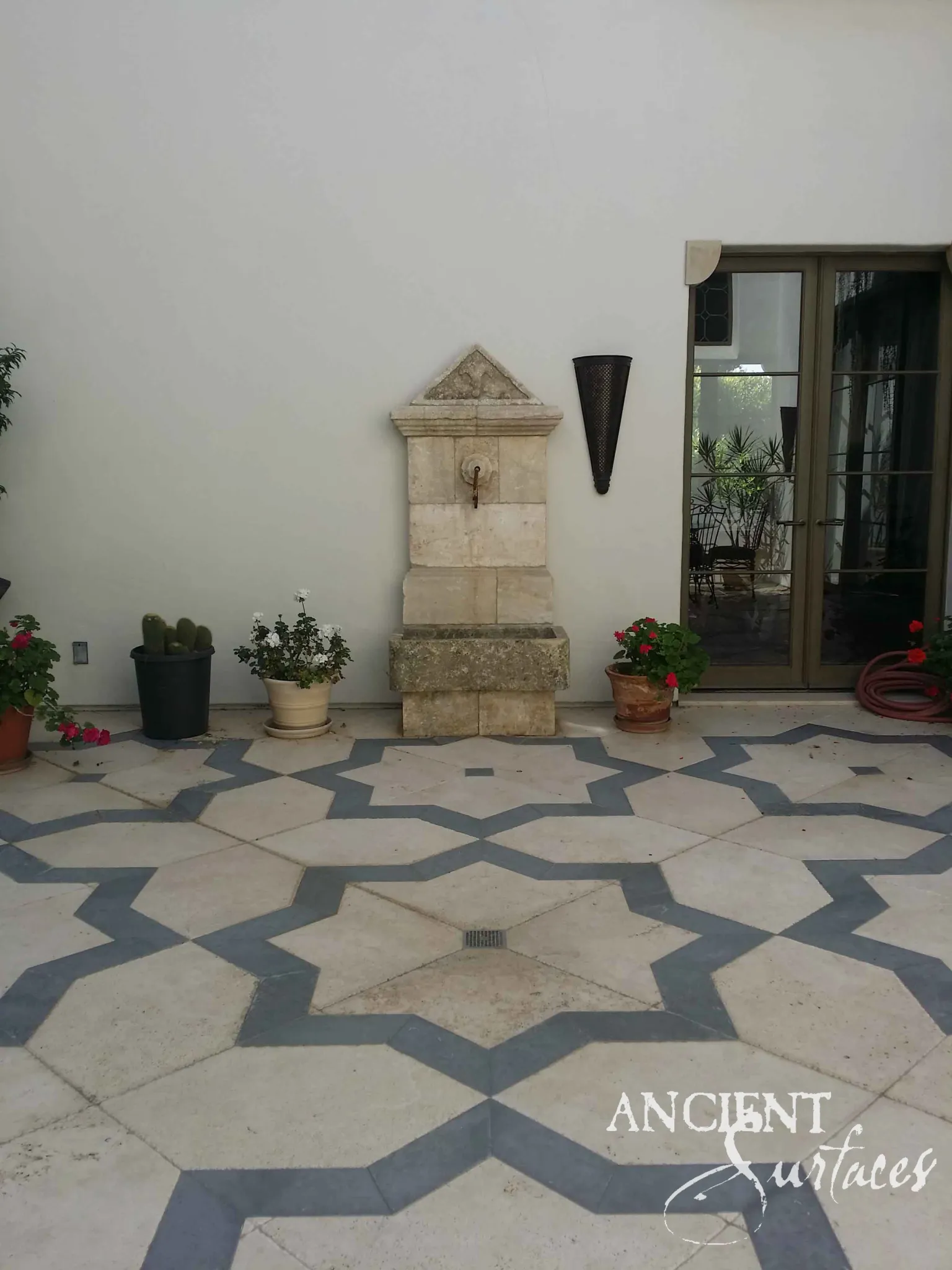 Cream antique limestone wall fountain with a carved lion's-head relief and stone basin